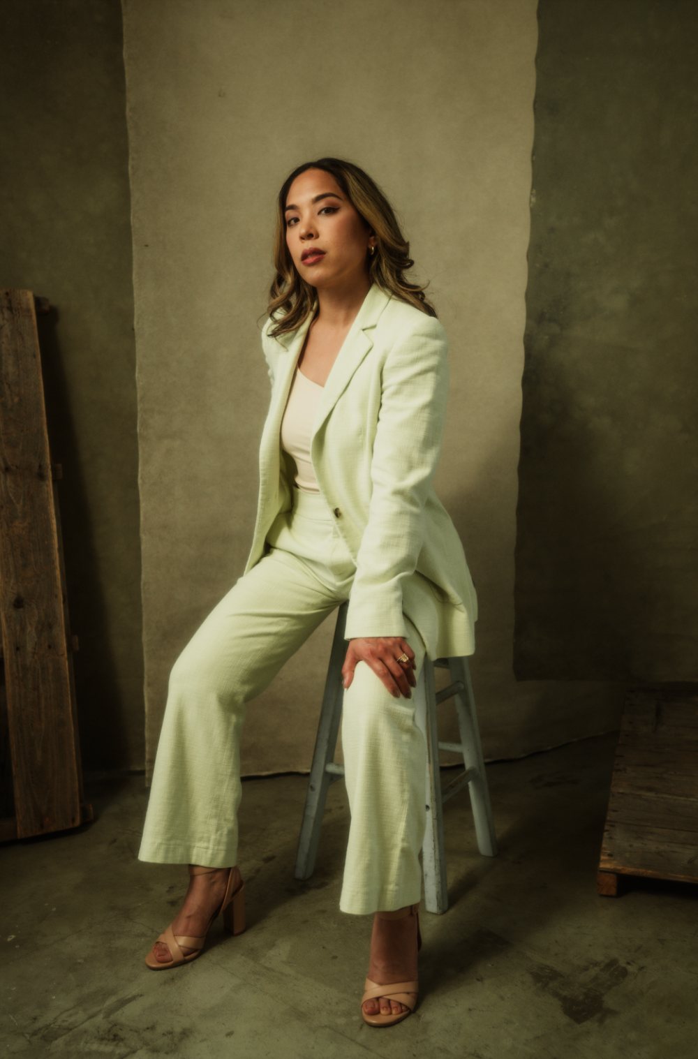 Charlene Platon in a pale mint suit, seated on a stool against a studio backdrop