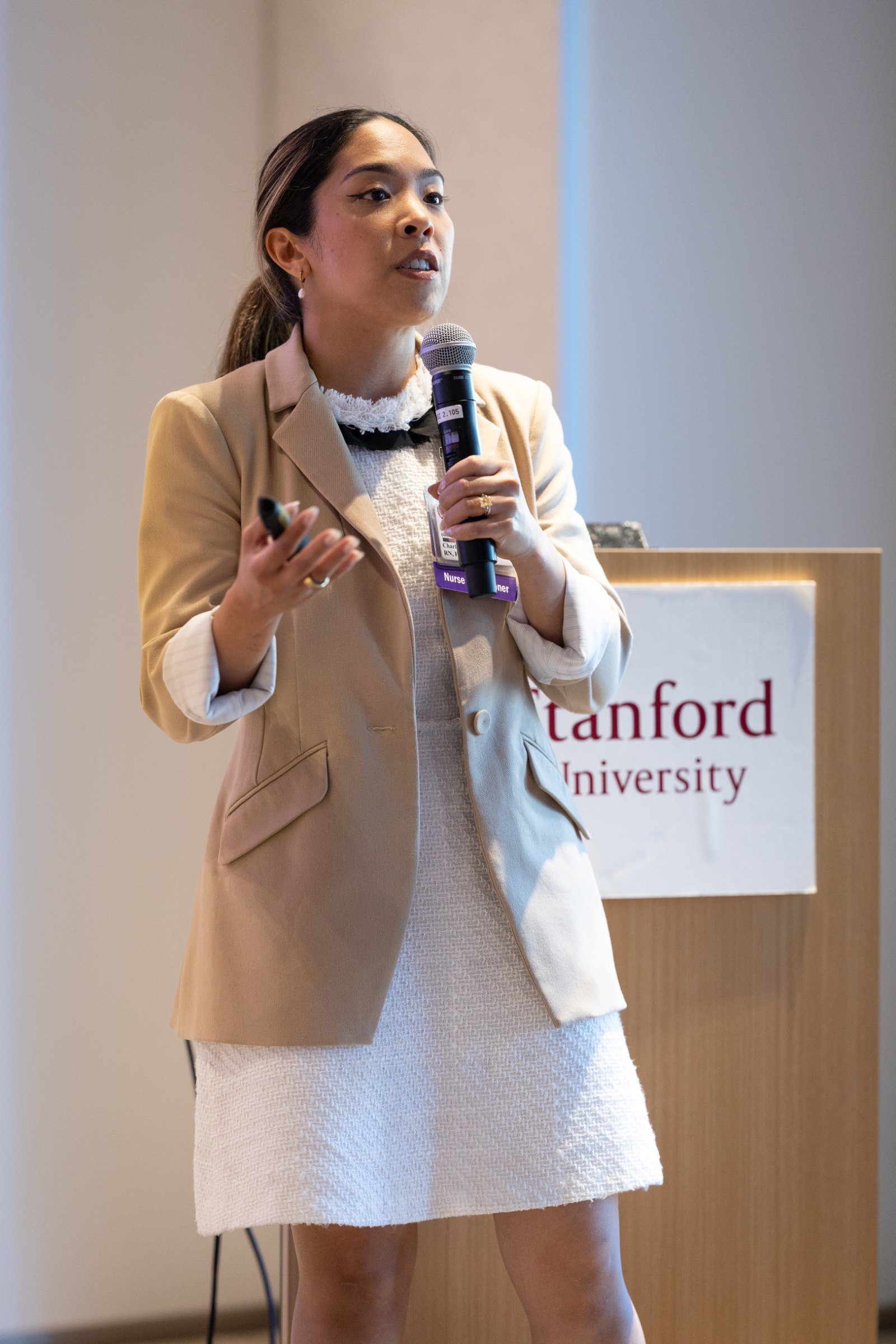 Charlene Platon speaking at a professional healthcare conference, microphone in hand